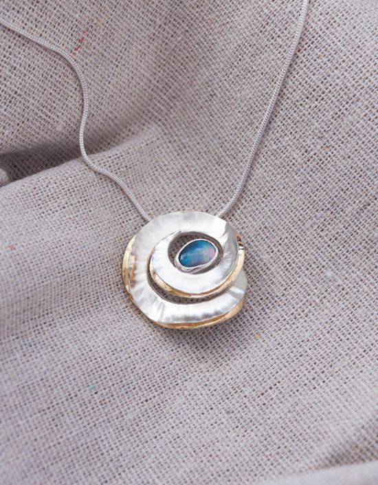 Handmade sterling silver swirl pendant with a solid opal and 18ct gold-plated folds, crafted in Orkney.