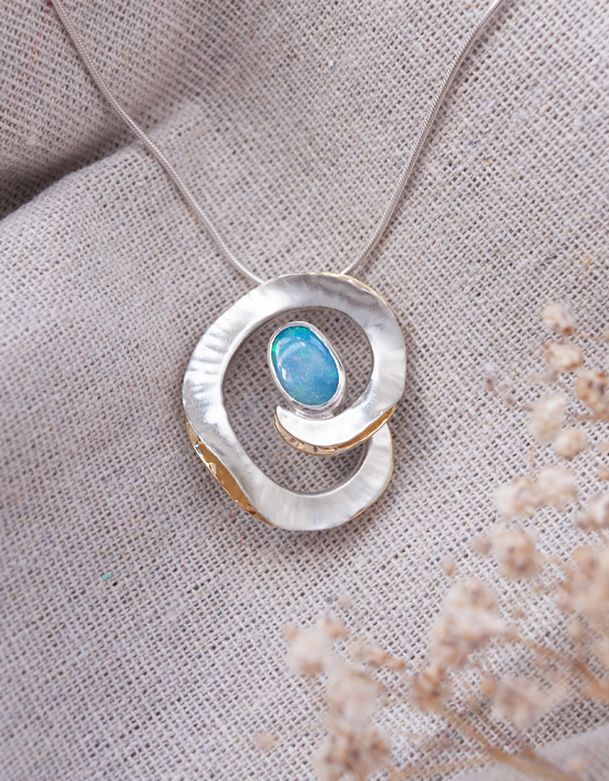 Sculptural sterling silver pendant featuring a blue green solid opal with 18ct gold-plated folds, handmade in Orkney.